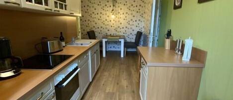 Una cocina con armarios de madera, una encimera y una zona de comedor con una mesa y sillas.
