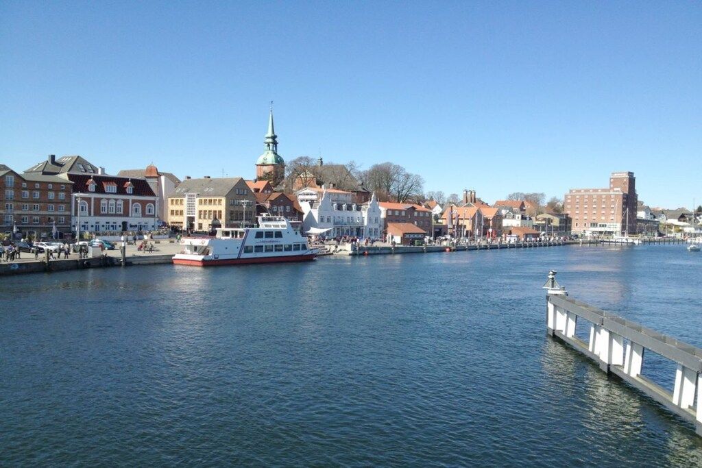 En flod med en båd ved et fortøjningsbro, omgivet af bygninger med forskellig arkitektur.