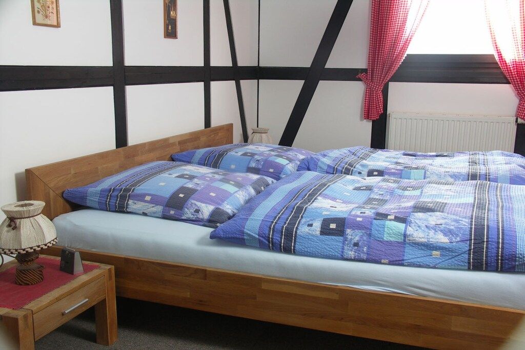 Ein Schlafzimmer mit einem hölzernen Bett, einem Nachttisch und einem roten Vorhang.