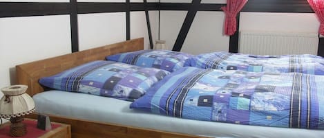 Quarto com cama de madeira, mesa de cabeceira e cortina vermelha.