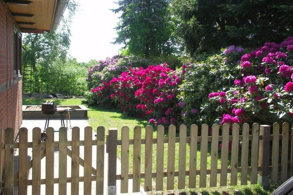 A wooden fence, a brick wall, and a garden with pink flowers.