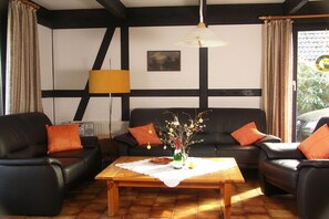 Ein Wohnzimmer mit zwei schwarzen Ledersofas, einem Holztisch und einer Lampe.