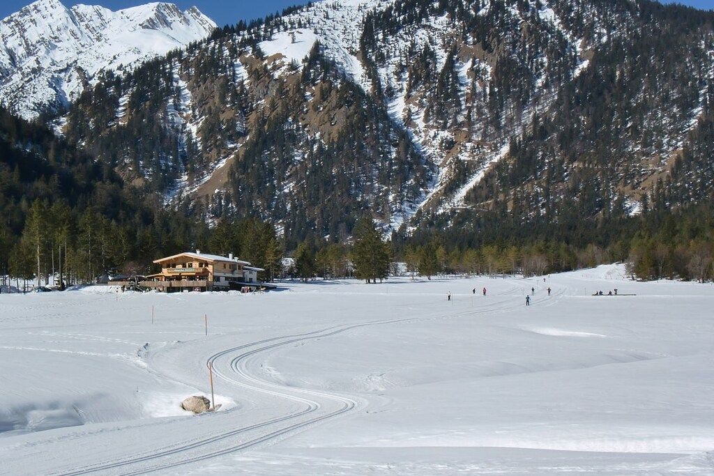 A snow-covered landscape with a lodge and ski tracks.