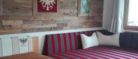 Una pared de madera con cuadros enmarcados, un sofá a rayas y una mesa de madera.