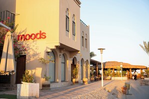 Un edificio con un letrero que dice 'moods', mesas al aire libre y plantas en macetas.