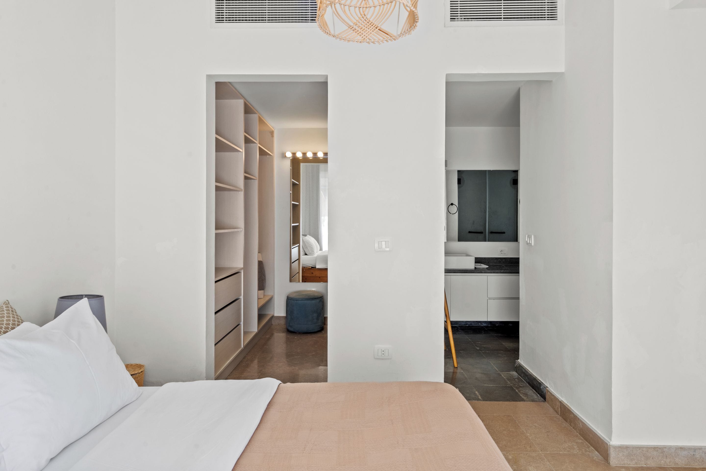 A bedroom with a bed, a wardrobe, and a bathroom visible through an open door.
