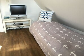 A bedroom with a bed, a television on a stand, and a small desk with a picture frame. - Holiday home in Zirchow with barbecue (Zirchow)