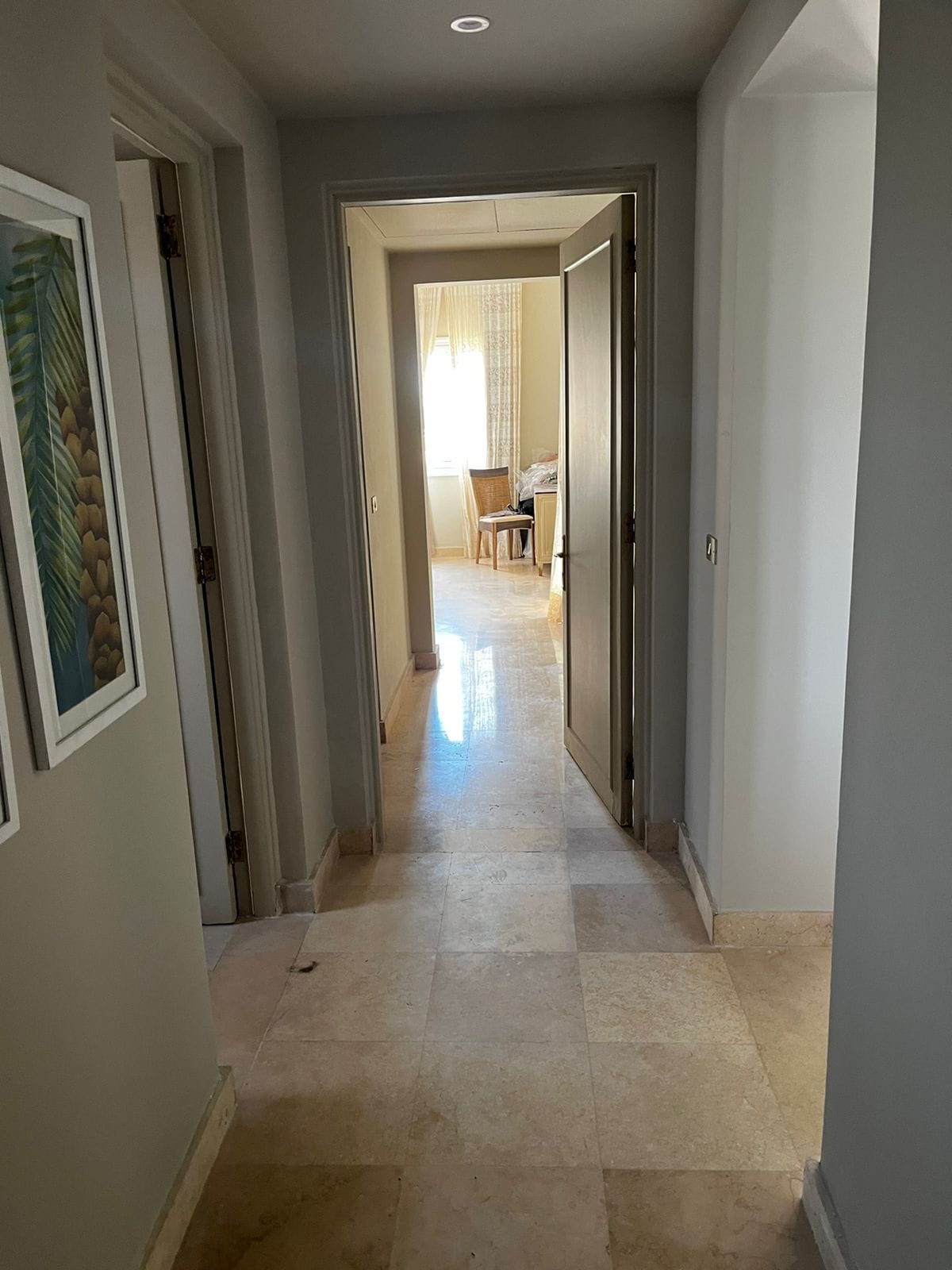 Un pasillo con piso de baldosas que conduce a una habitación con una silla y una mesa.