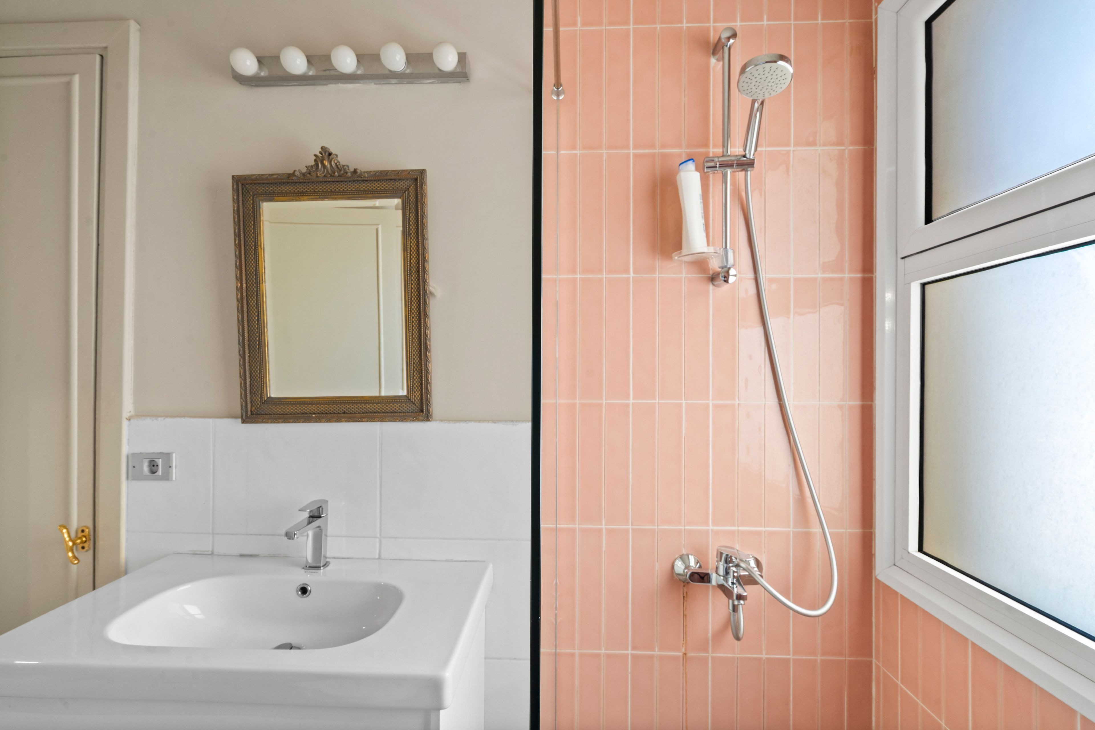 A bathroom with a sink, mirror, and shower.