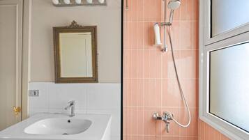 A bathroom with a sink, mirror, and shower.