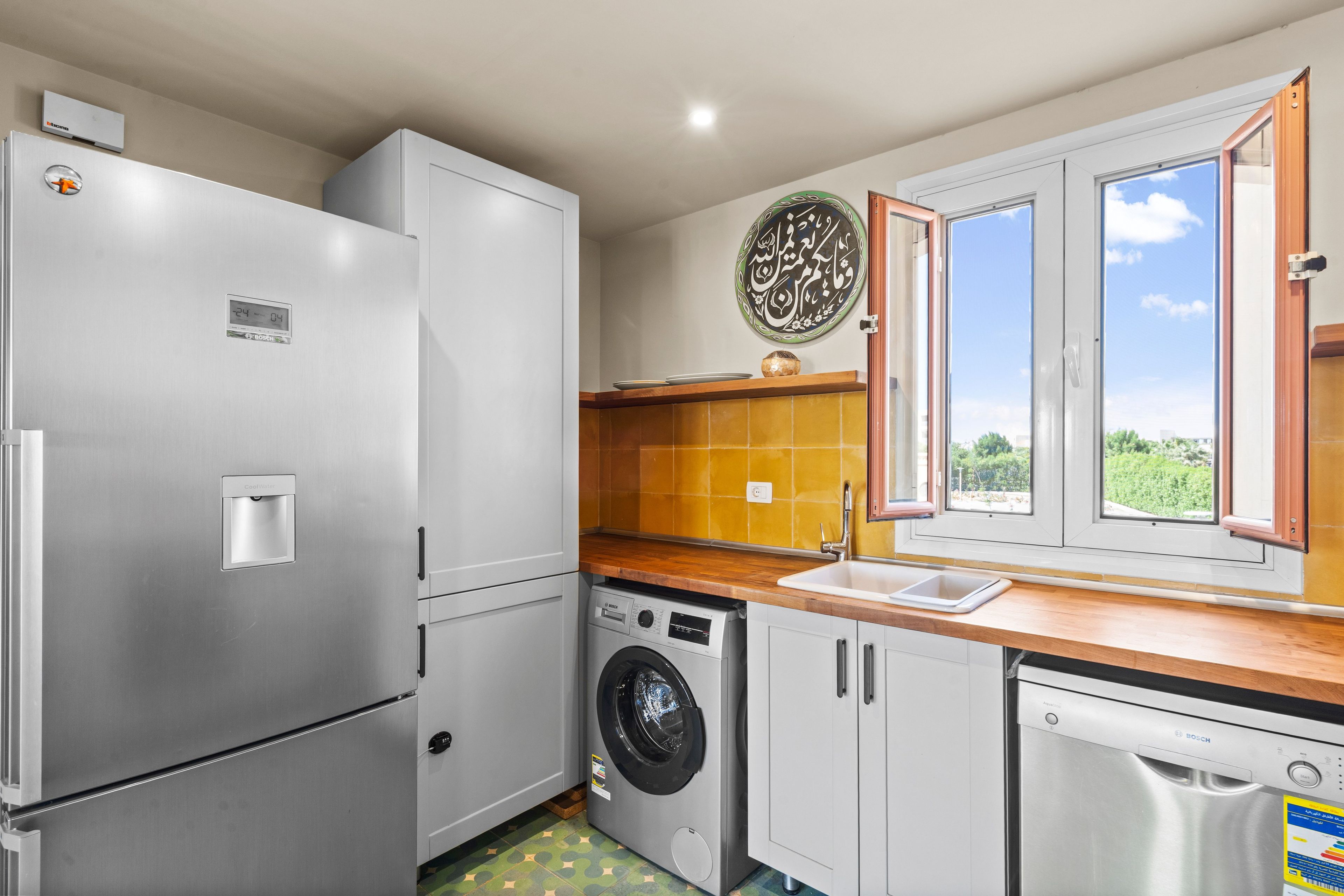 A compact kitchen with a refrigerator, washing machine, and dishwasher.