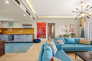 Ein modernes Wohnzimmer mit einer Couch, einem Couchtisch und einer Küchenzeile mit Fliesenrückwand.