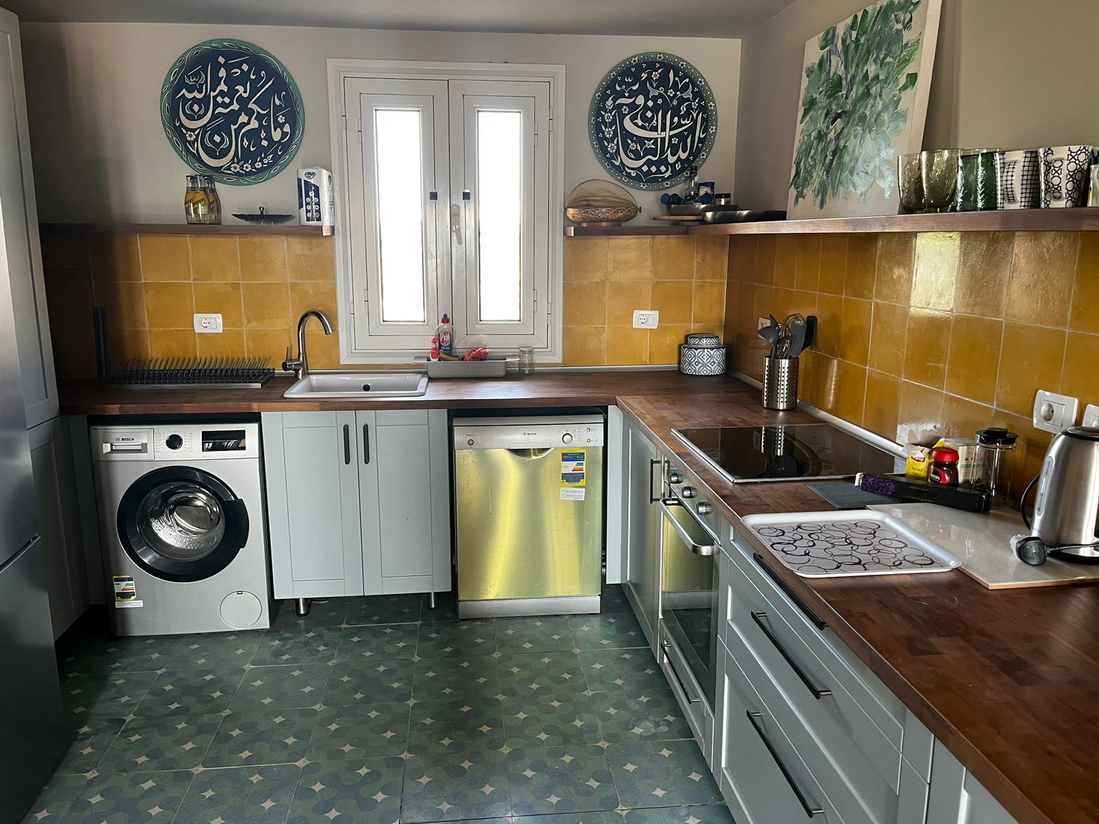 A kitchen with a washing machine, dishwasher, oven, and a sink.