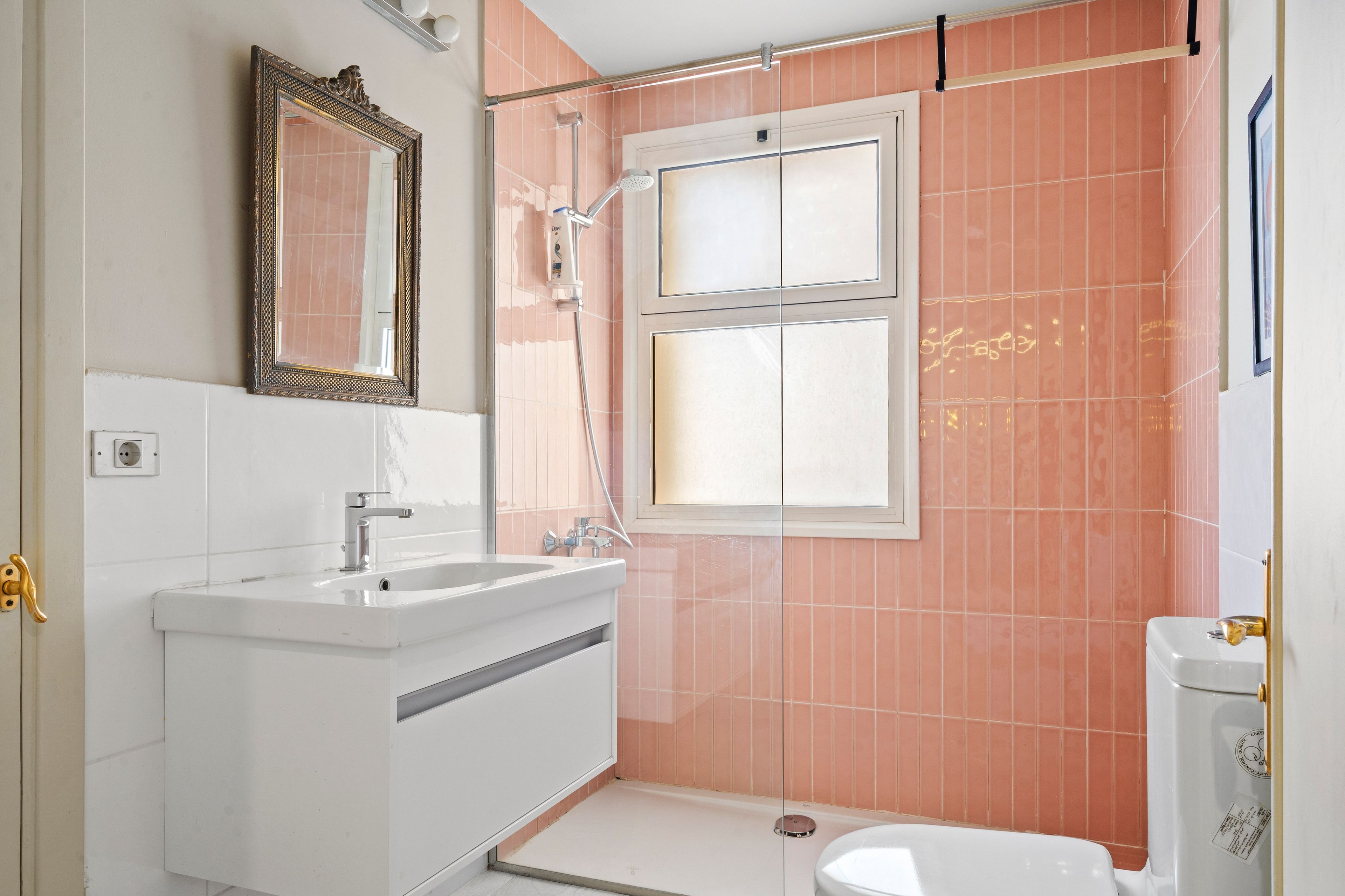A bathroom with a white sink, a mirror, a shower, and a toilet.
