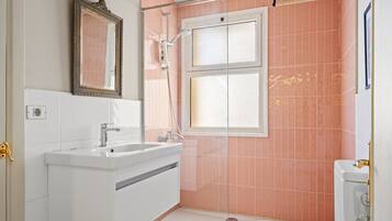 A bathroom with a white sink, a mirror, a shower, and a toilet.