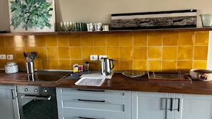Cozinha com fogão, forno e diversos utensílios sobre o balcão.