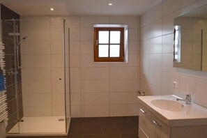 Un bagno con cabina doccia in vetro, una piccola finestra e un lavabo con specchio.