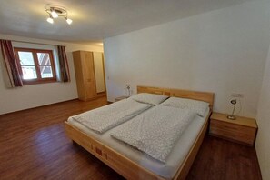 Una camera da letto con un letto di legno, un armadio, un comodino e una finestra con tende.