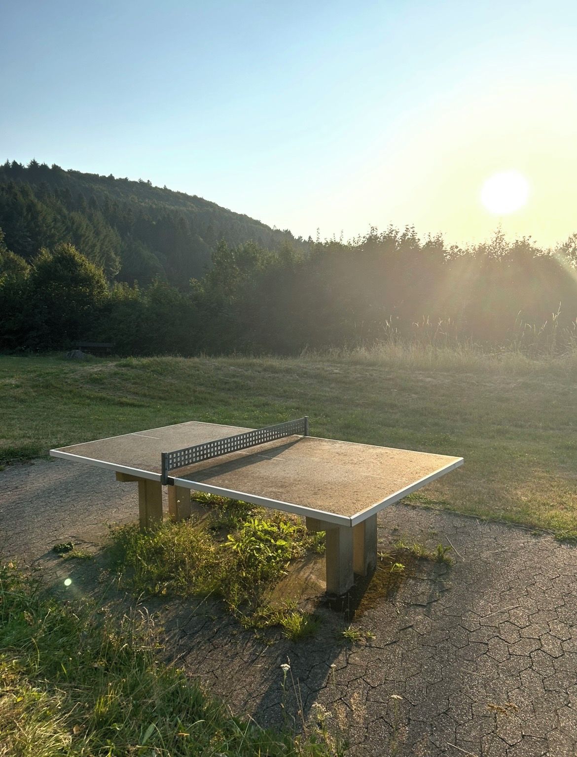 Ein Pingpongtisch in einer Außenumgebung bei blauem Himmel und Sonnenschein.
