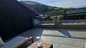 An outdoor seating area with a table and chairs, a view of the surrounding landscape, and a clear sky.