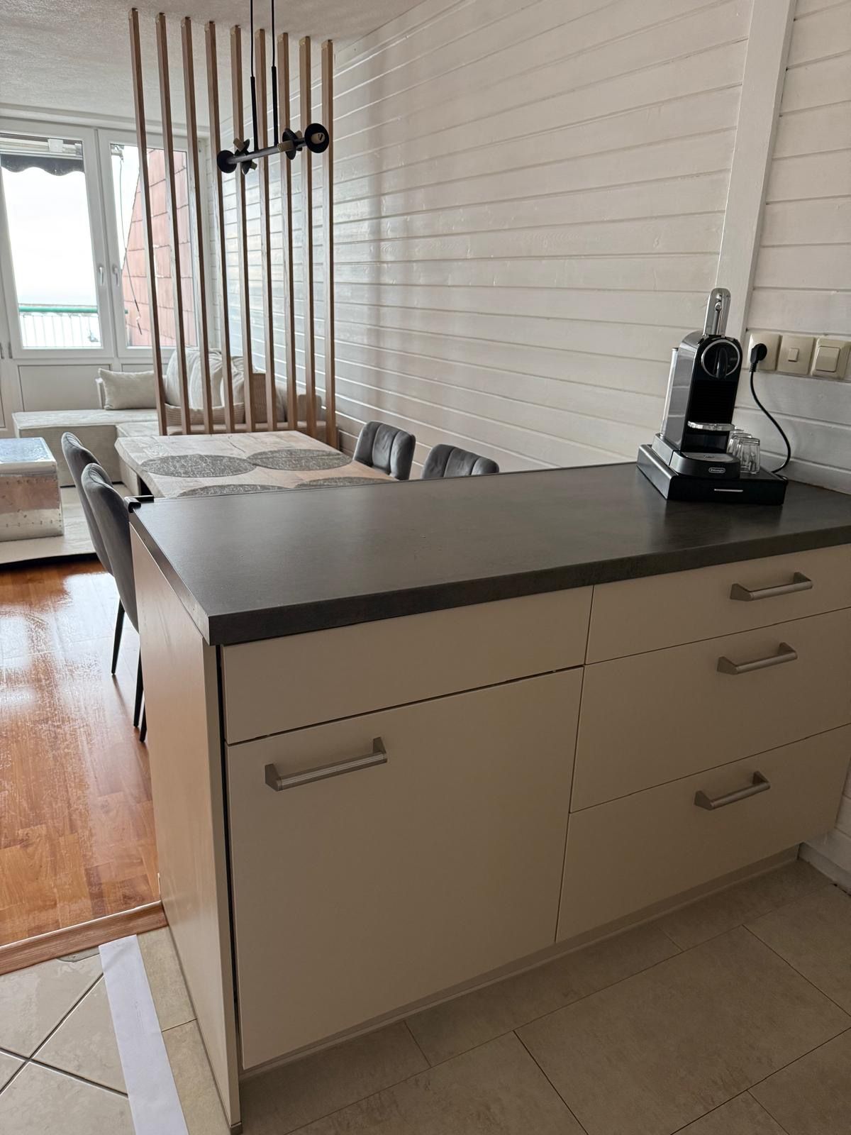 Eine moderne Küche mit schwarzer Arbeitsplatte, weißen Schränken und einer Kaffeemaschine.
