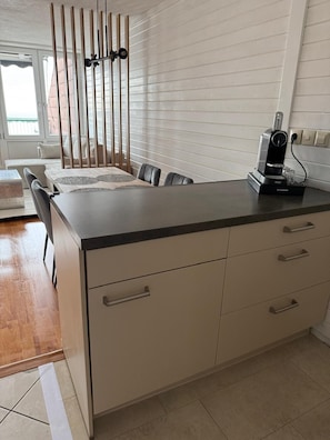 Una cocina moderna con encimera negra, armarios blancos y una cafetera.