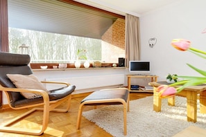 Ein modernes Wohnzimmer mit einem schwarzen Ledersofa, einem Holztisch und einem Fernseher auf einem Schrank.