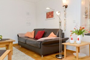 Ein modernes Wohnzimmer mit einer Ledersofa, einer Stehlampe und einem kleinen Tisch mit Vasen.