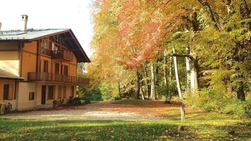 A two-story building with a balcony, surrounded by trees with autumn foliage.