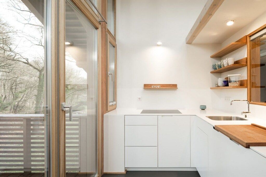 A modern kitchen with white cabinetry, a wooden countertop, and a built-in shelf unit.