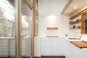 Una cocina moderna con armarios blancos, encimera de madera y una unidad de almacenamiento empotrada.