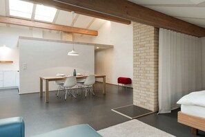 Habitación moderna con zona de comedor, cama y pared de ladrillo.