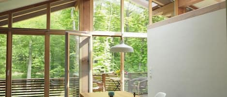 A dining area with a long table, chairs, and a hanging light fixture.