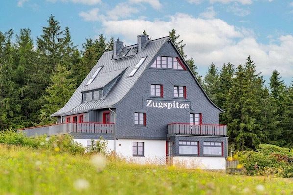 A two-story building with a sloped roof, a balcony, and a name 'Zugspitze' on the side.