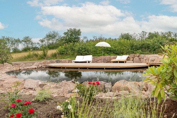 A pool area with lounge chairs and a sun umbrella.