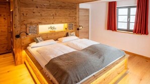 A wooden-framed bed with a headboard, a bedside table, and a window with red curtains.