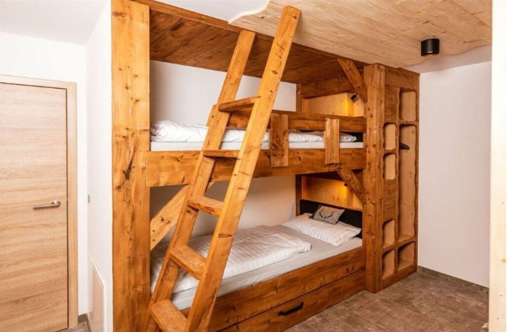 Ein Stockbett mit Holzlade, einer kleinen Schublade und einem Kopfteil mit Leuchte.