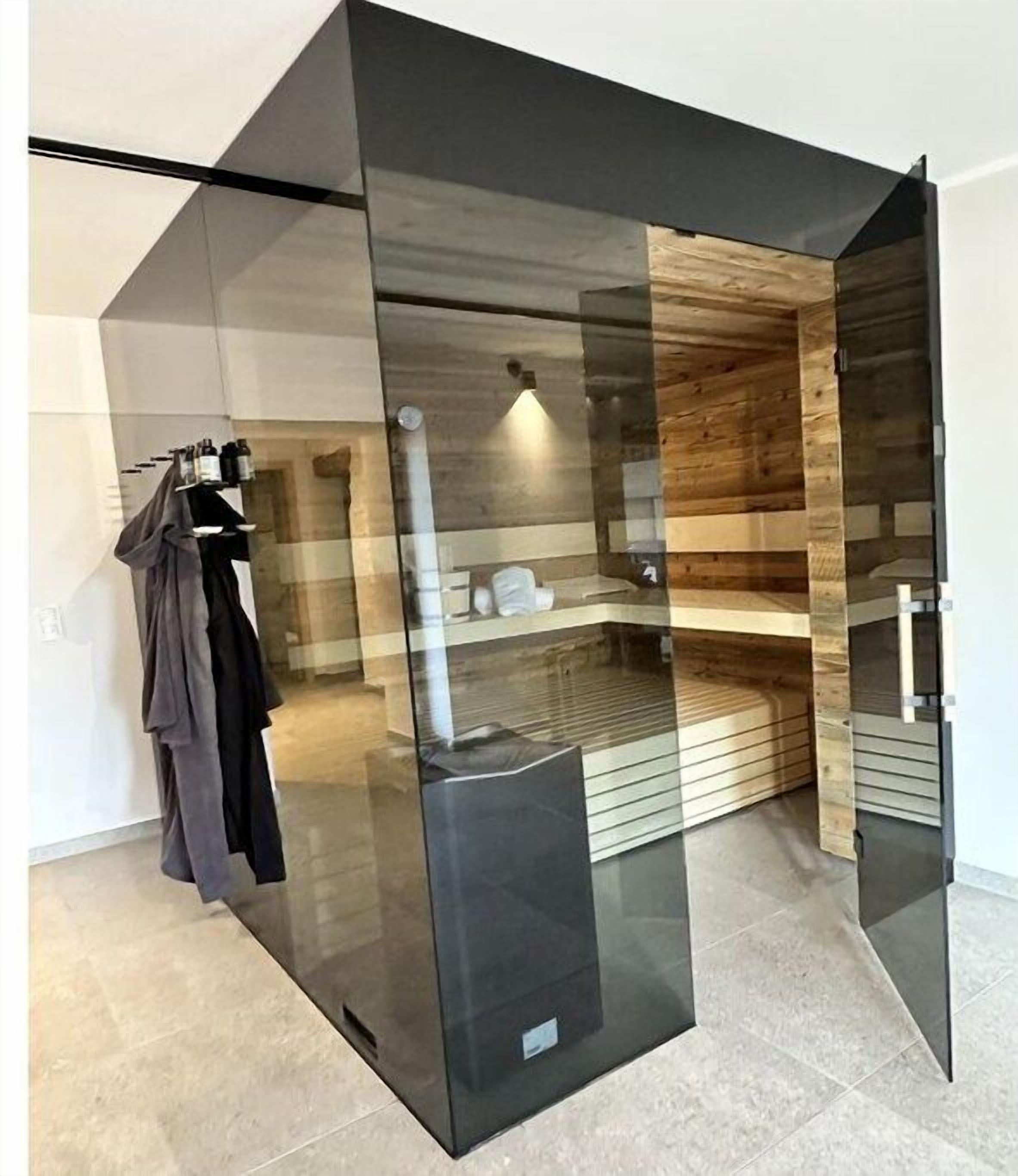 Ein modernes Badezimmer mit Glastrennwand, Holzelementen und einem Handtuchhalter.