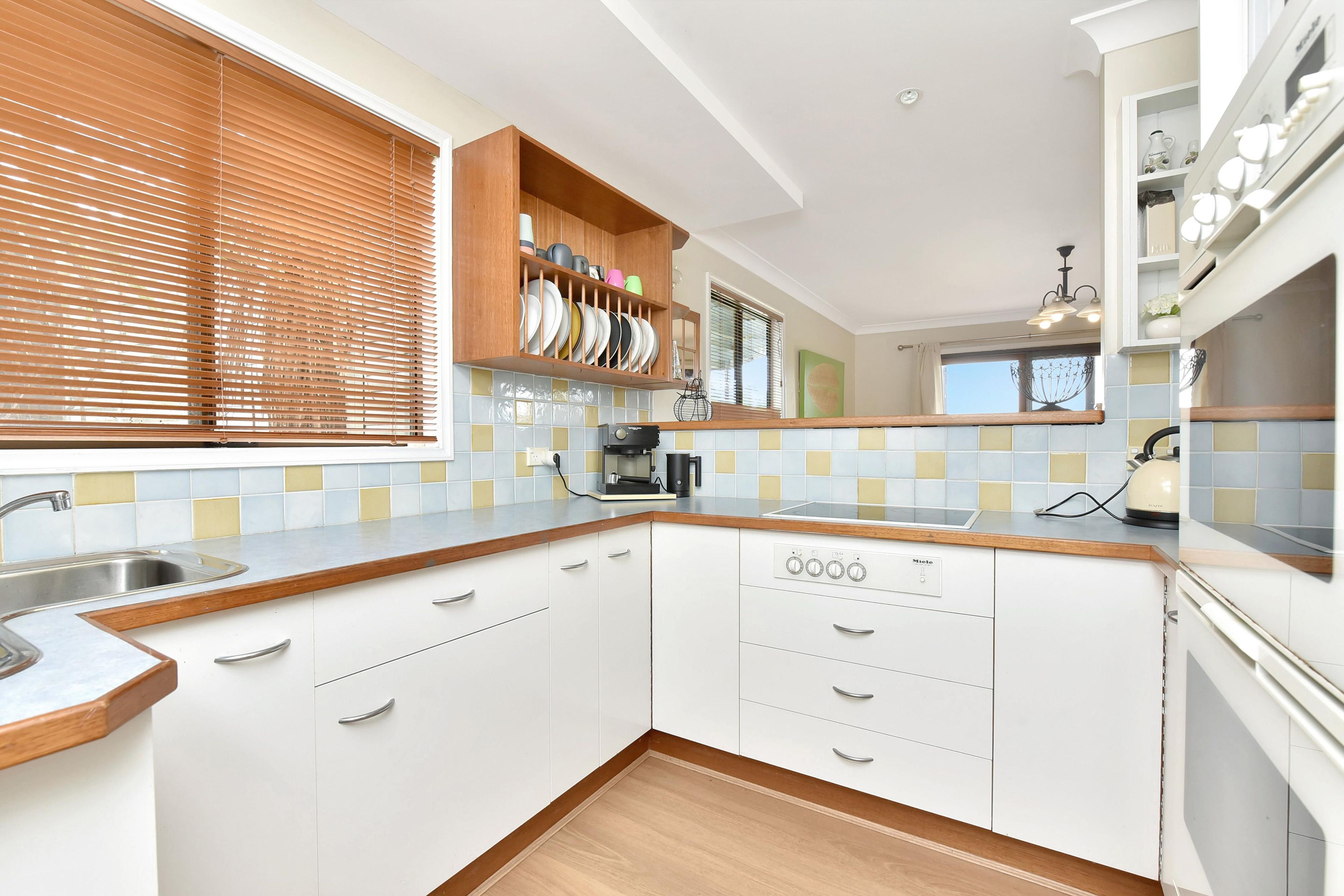 Een moderne keuken met witte kasten, een inbouwoven en een koffieapparaat.