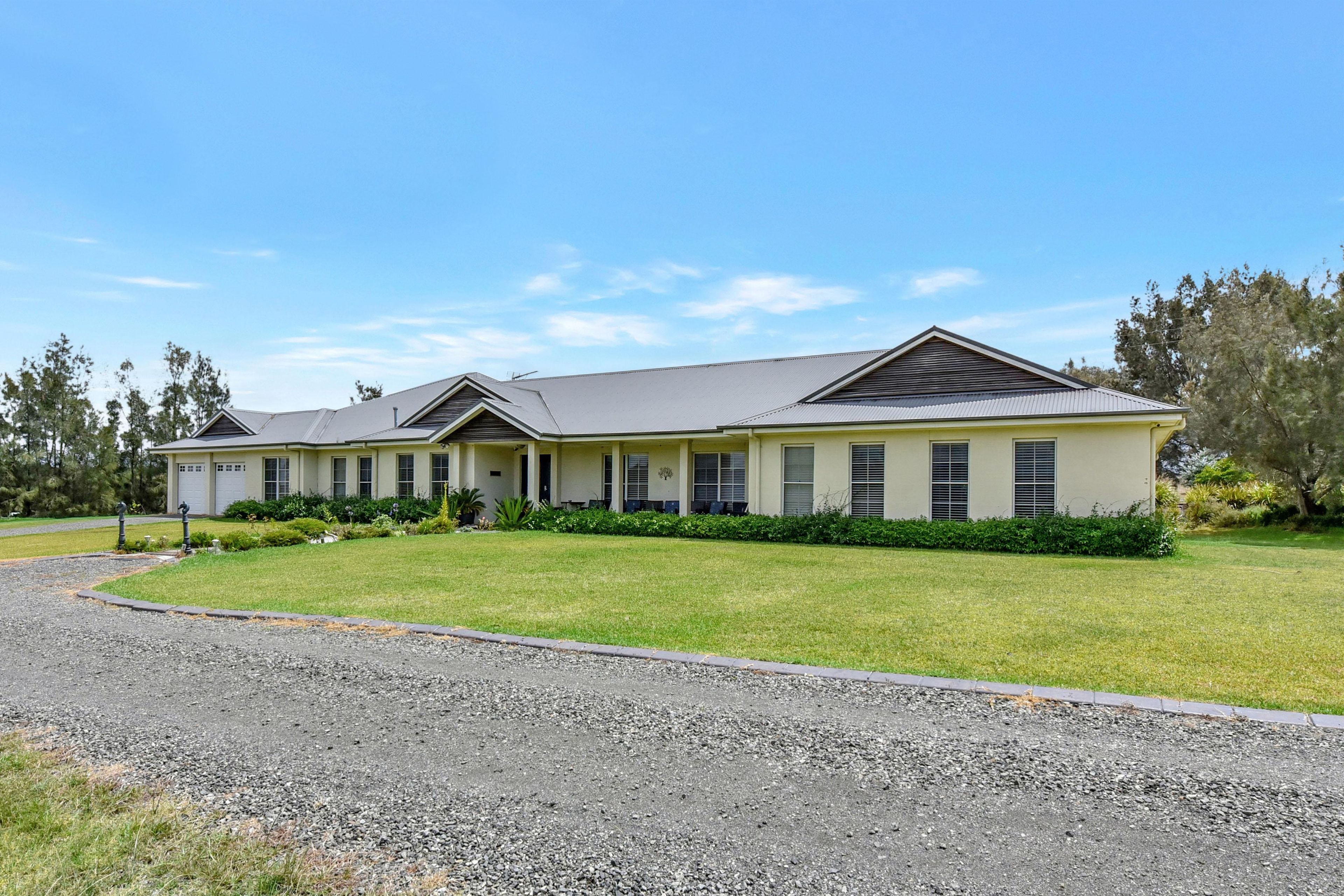 A two-story building with a covered patio area and a gravel driveway.