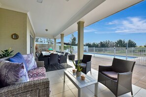 A covered outdoor area with a dining table, chairs, and a pool in the background. - Olive Ridge Homestead - Set across 43 peaceful acres in the heart of Pokolbin (Rothbury)