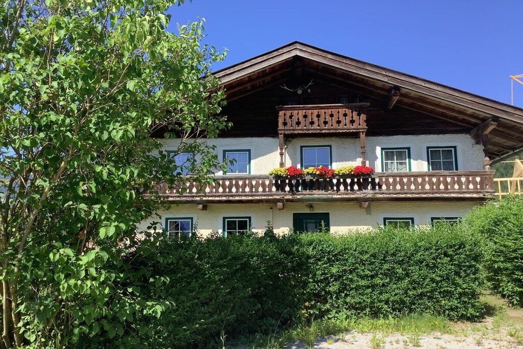 Un immeuble de deux étages doté d’un balcon, entouré de verdure.