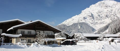 A snow-covered mountain lodge with a wooden exterior and multiple windows.