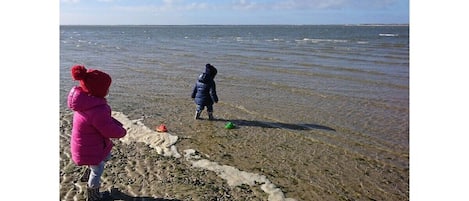 Dos niños jugando cerca del agua bajo un cielo despejado.