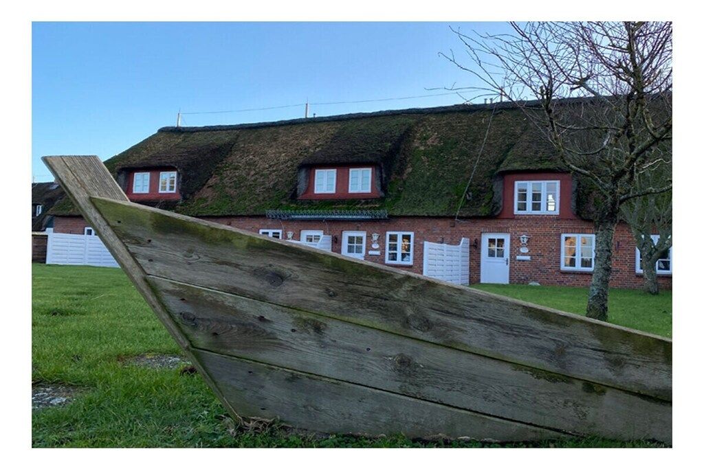 A traditional brick house with a thatched roof and a wooden deck.