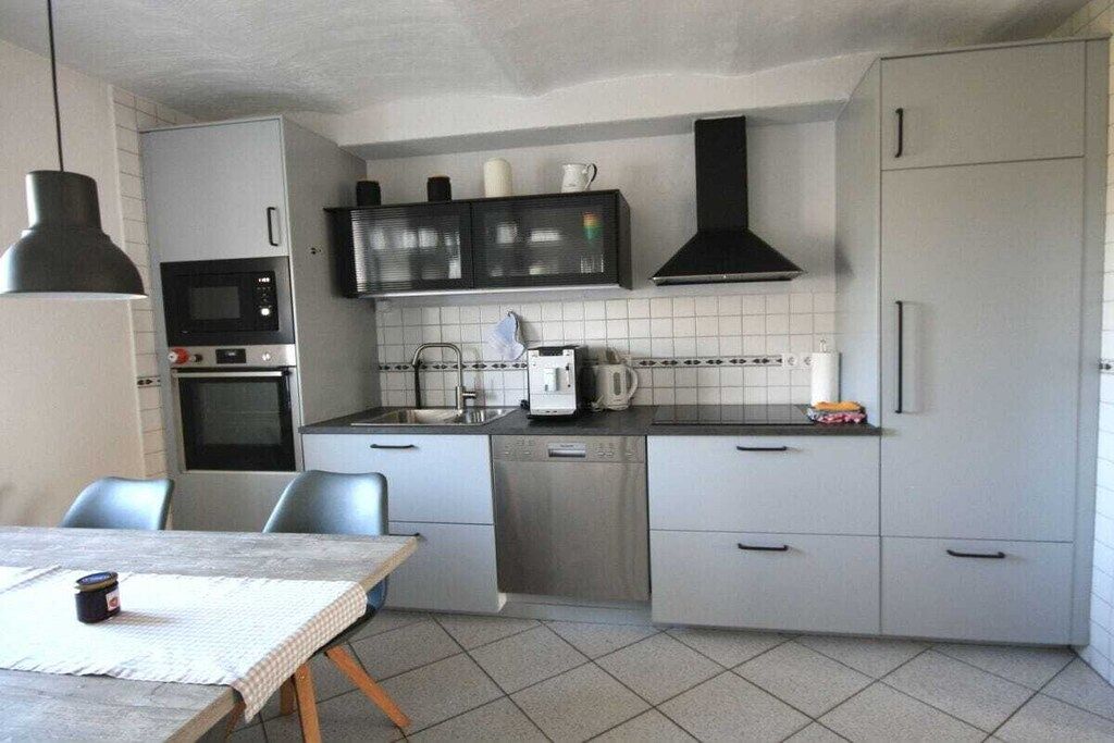 A compact kitchen with a microwave, oven, sink, and a coffee maker.