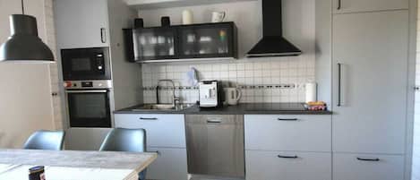 Cocina compacta con microondas, horno, fregadero y cafetera.