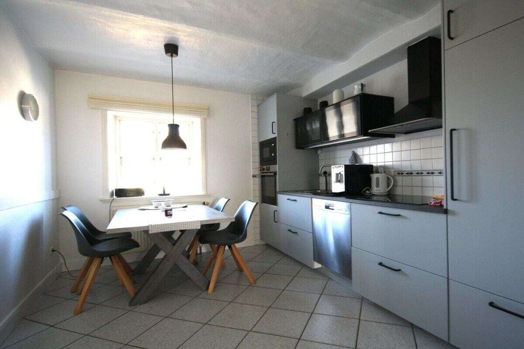 A compact kitchen with a dining table, chairs, and basic appliances.