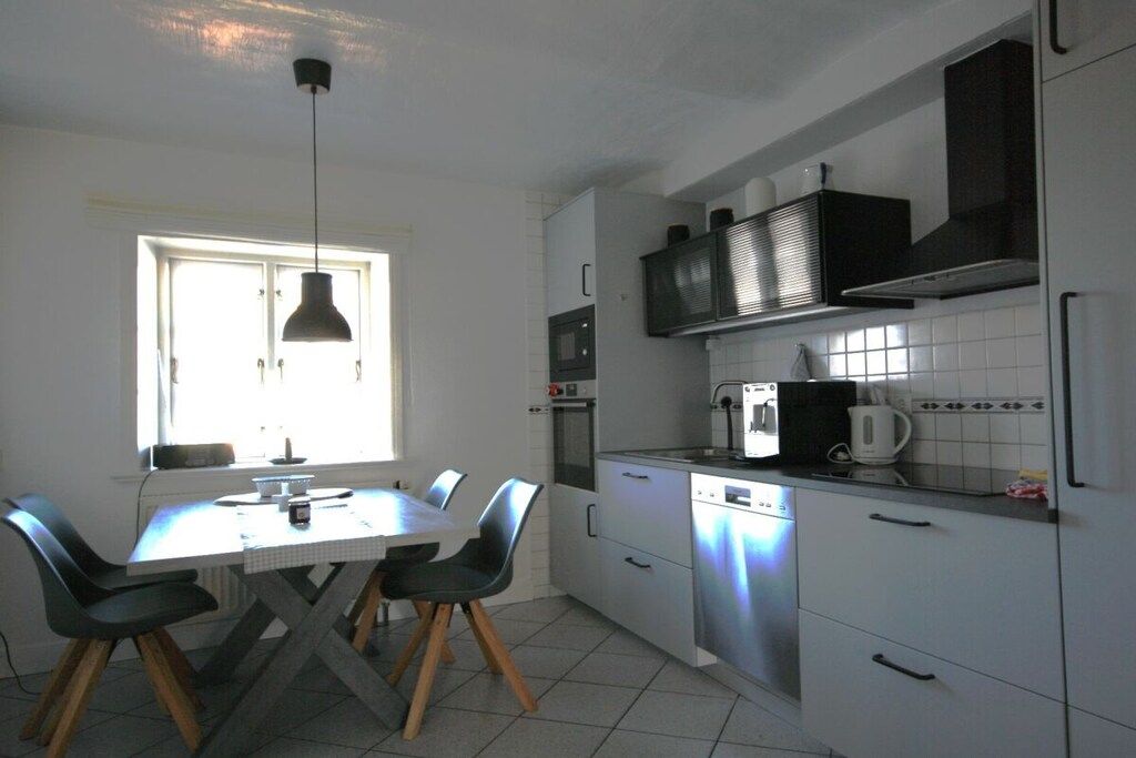 A kitchen with a dining table, chairs, a window, and modern appliances.