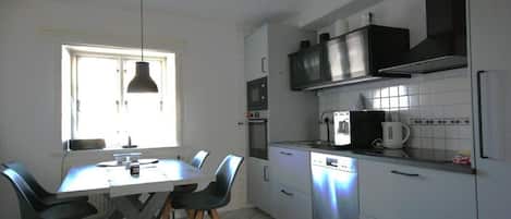 A kitchen with a dining table, chairs, a window, and modern appliances.